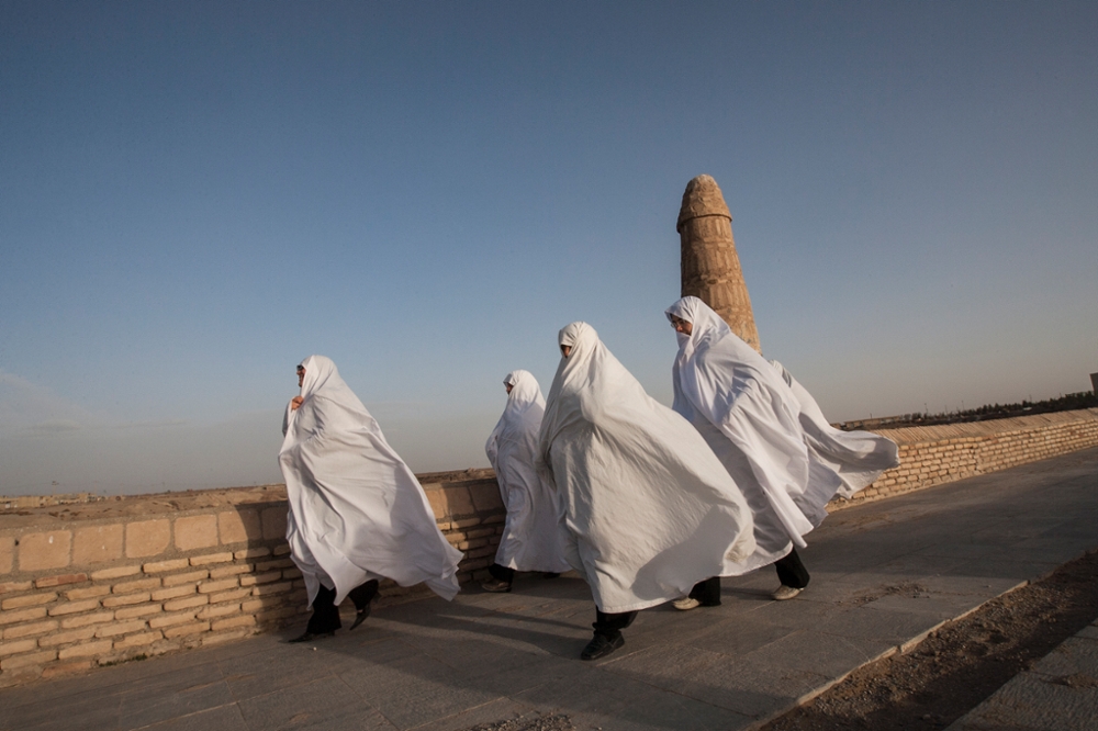 Iran, Varzaneh, Isfahan Province, A group of women, dressed in white chadors, crossing the Varzaneh bridge. Traditionally, in the region, white is worn to ward off evil.