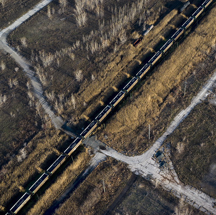 Petcoke filled train moving through brown field, former steel mill site