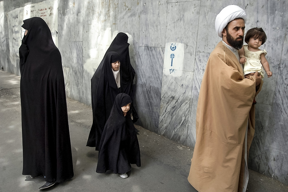 Tehran, Iran. A cleric and his family walking on Valiasr Street.