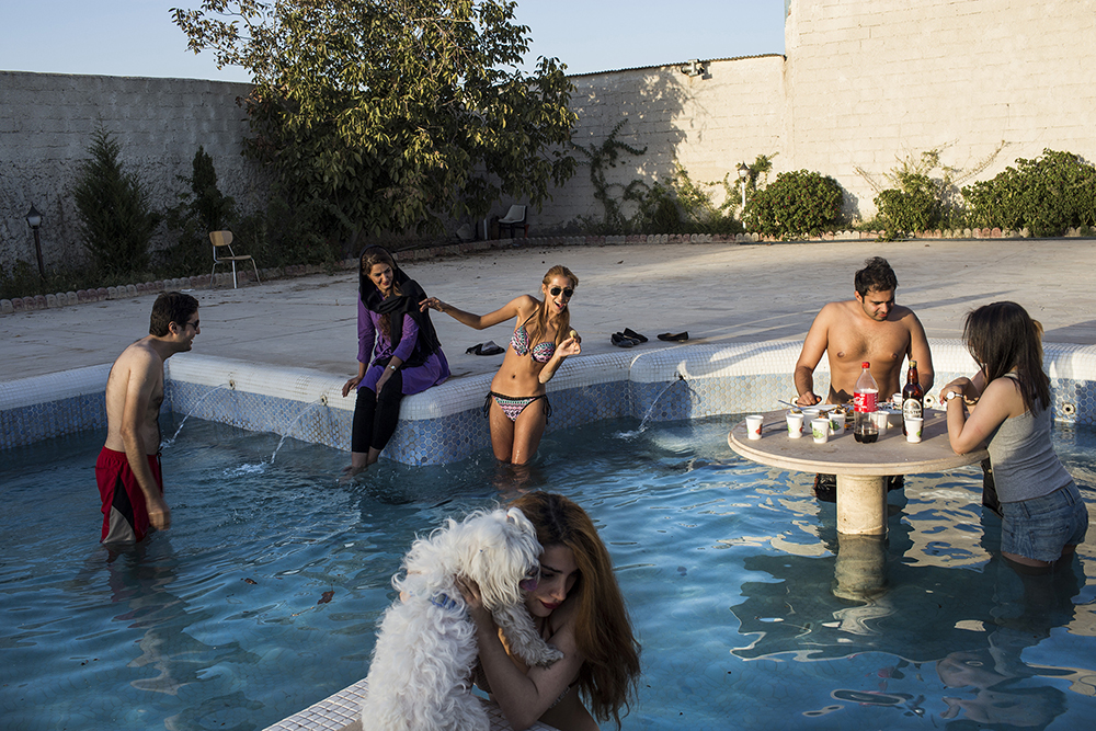 Tehran, Iran. A group of young people relax and drink in a swimming pool in Tehran.