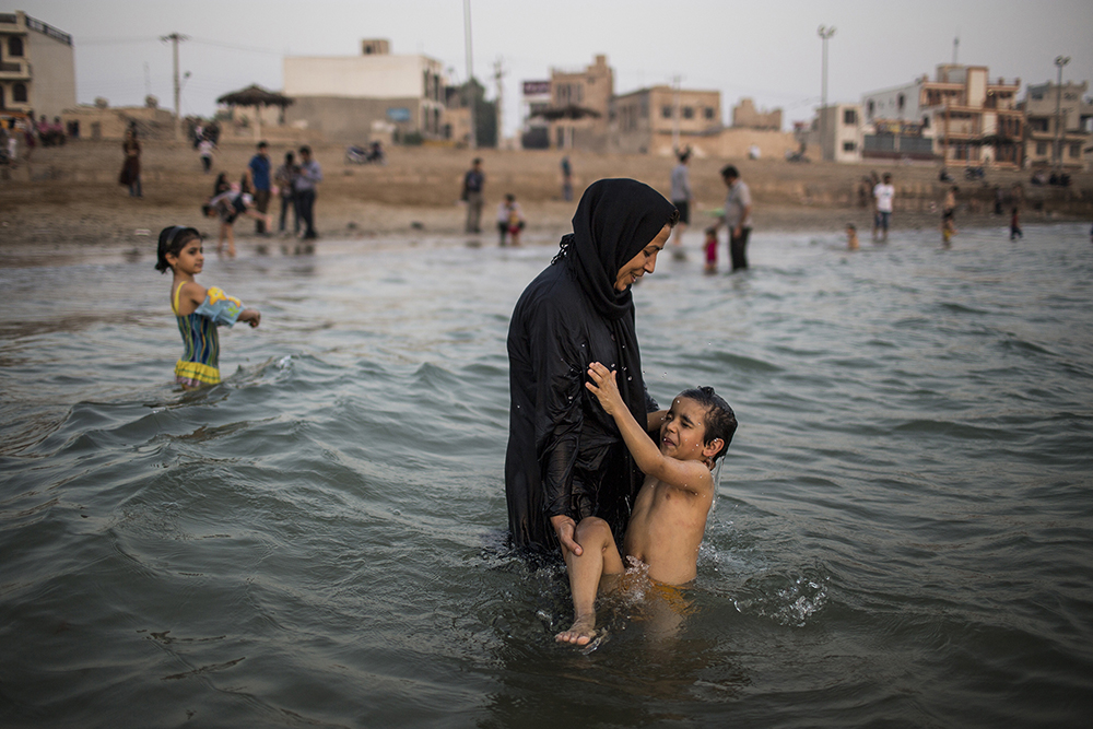 Bushehr, Iran. A woman wading in the Persian gulf with her son.