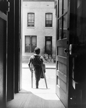 Washington, D.C. Young boy standing in the doorway of his home on Seaton Road in the northwest section. His leg was cut off by a streetcar while he was playing in the street