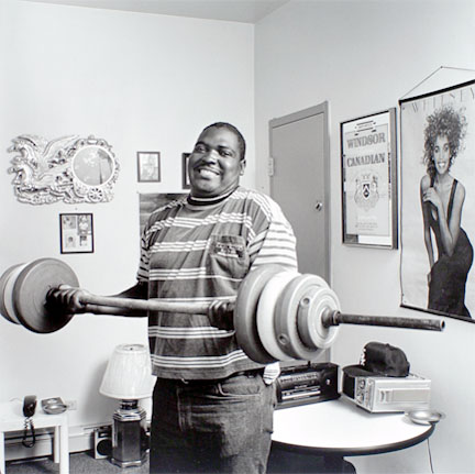 Young man lifting weights in his room at the Harold Washington SRO, from the Edge of Shelter Project